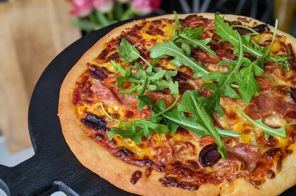 Delicious homemade gluten-free pizza slice on a wooden board, highlighting quality flour crust.
