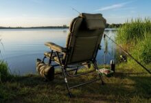 Comfortable padded fishing chair with lumbar support and armrests set up beside calm lake