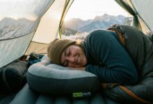 Compact memory foam camping pillow rolled inside a tent at dusk.