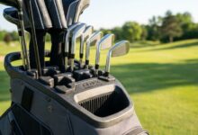 Golfer organizing clubs securely inside a T-lock cart bag on a course.